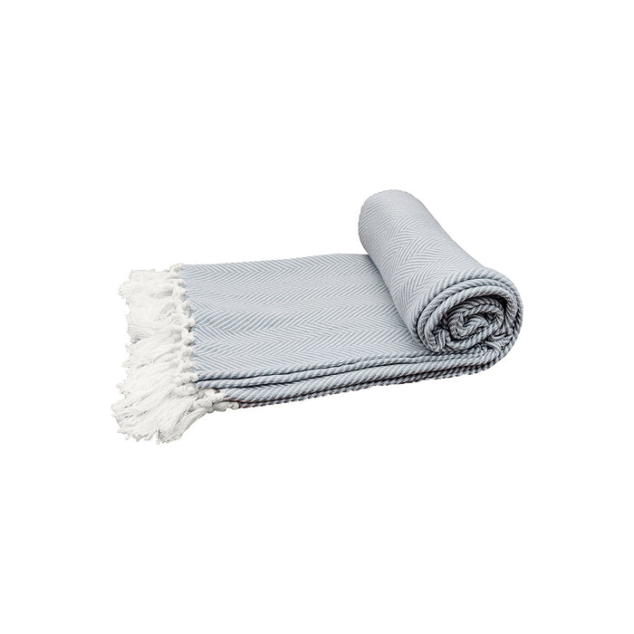 A rolled up blue throw blanket with a herringbone pattern and white fringes on a light background.